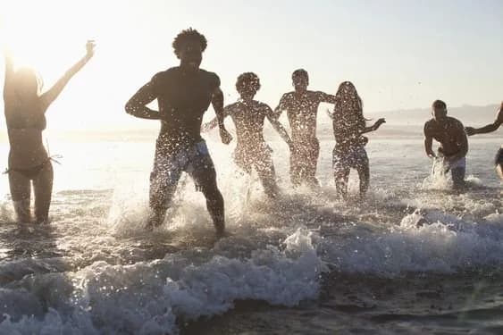 A group of friends running out of the surf at the beach in golden light