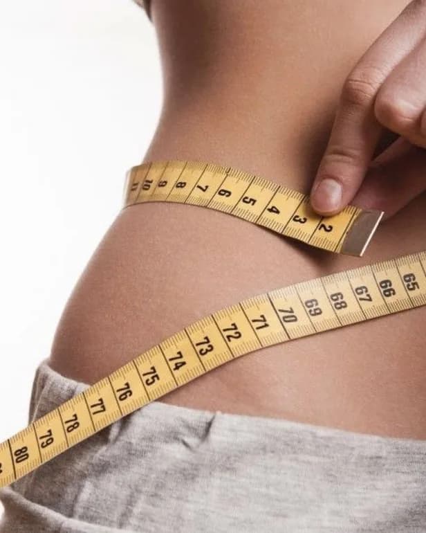 Person measuring their waist with a yellow measuring tape