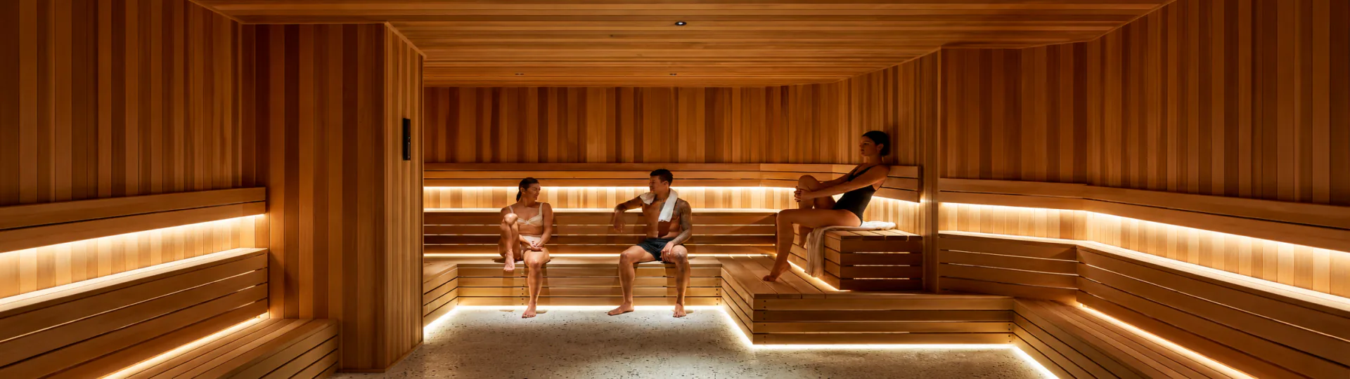 Three people relaxing on the benches of a warm timber sauna